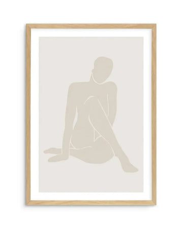 Framed art print featuring a minimalist silhouette of a seated female figure in soft beige tones against a light cream background. The figure is rendered in simplified, flowing lines with subtle shading that creates dimension. Natural wood frame with white border surrounding the artwork. The overall composition has a calm, contemplative mood with a contemporary aesthetic.
