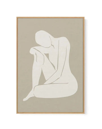 Framed canvas art print featuring a minimalist line drawing of a seated female figure in white against a soft beige background. The figure is rendered in a continuous line style with subtle grey contour lines defining the form. The canvas is mounted in a natural wood frame with a simple border. The overall composition conveys a contemplative mood through the figure's bowed posture and graceful curved lines.