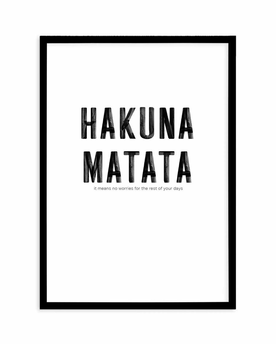 Framed art print with black border displaying the text "HAKUNA MATATA" in large, bold, hand-drawn style lettering with wood grain texture effect. Below in smaller gray text reads "it means no worries for the rest of your days." White background with minimalist design centered on the frame.