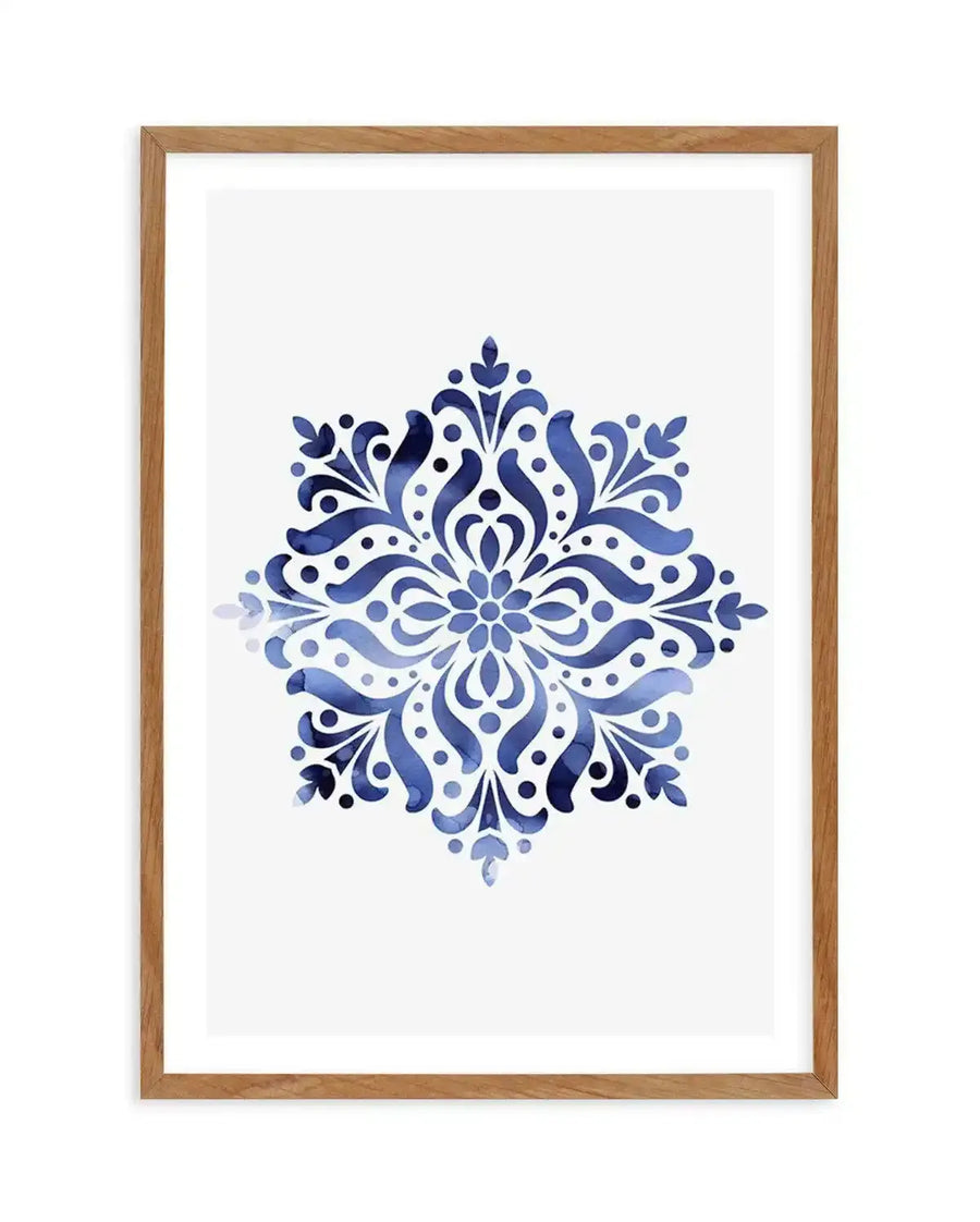 Watercolour art print featuring a symmetrical mandala-like floral motif in varying shades of deep blue and indigo on a white background, displayed in a natural oak frame with white border.