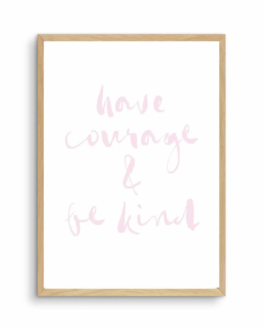 Art print with handwritten-style text in soft blush pink and light gray reading "have courage & be kind" on a white background, displayed in a natural wood frame with a white border.
