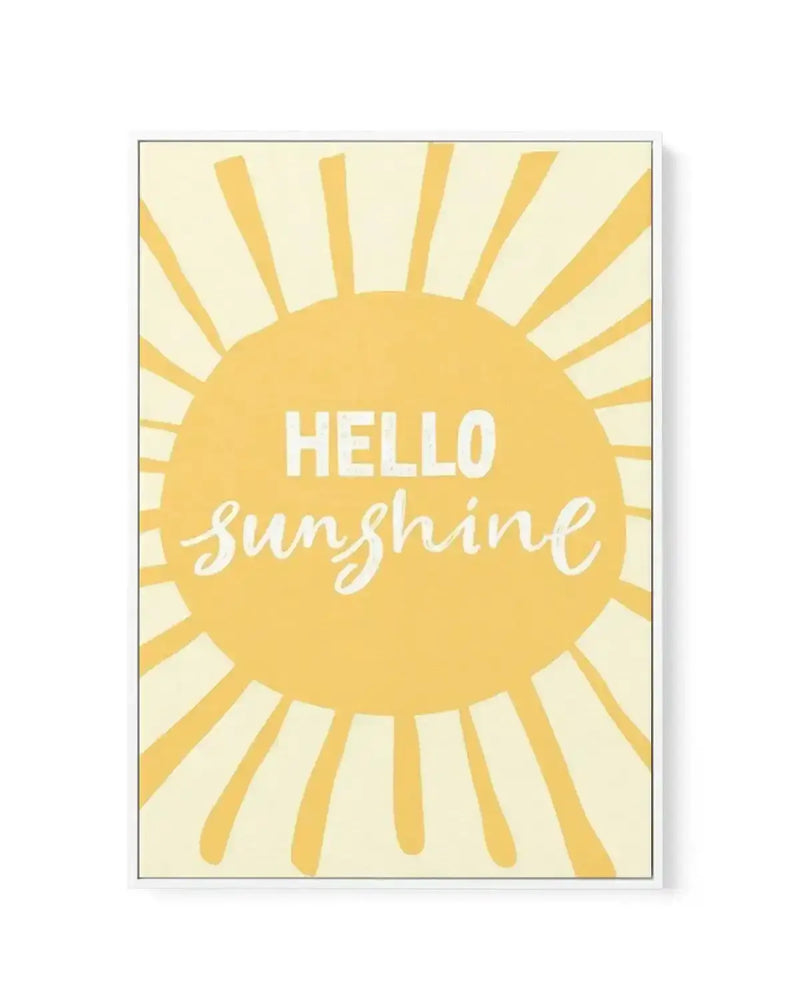 Framed canvas art print featuring a large golden-yellow sun with radiating rays in the center of a cream-colored background. "HELLO" appears in white capital letters in the upper portion of the sun, with "sunshine" written in flowing white script below it. The sun has a solid circular center with alternating thick and thin rays extending outward. The canvas is surrounded by a thin gray frame with a white border.