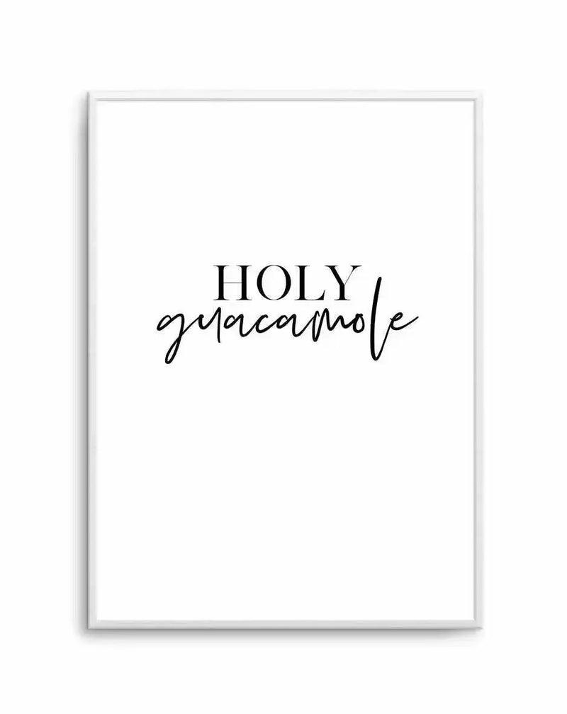White framed art print featuring "HOLY guacamole" in black text. The word "HOLY" appears in serif capitals, while "guacamole" is written below in a flowing cursive script. The design is minimalist with ample white space on a white background, displayed in a light gray or silver frame with a subtle shadow effect visible on the edges.