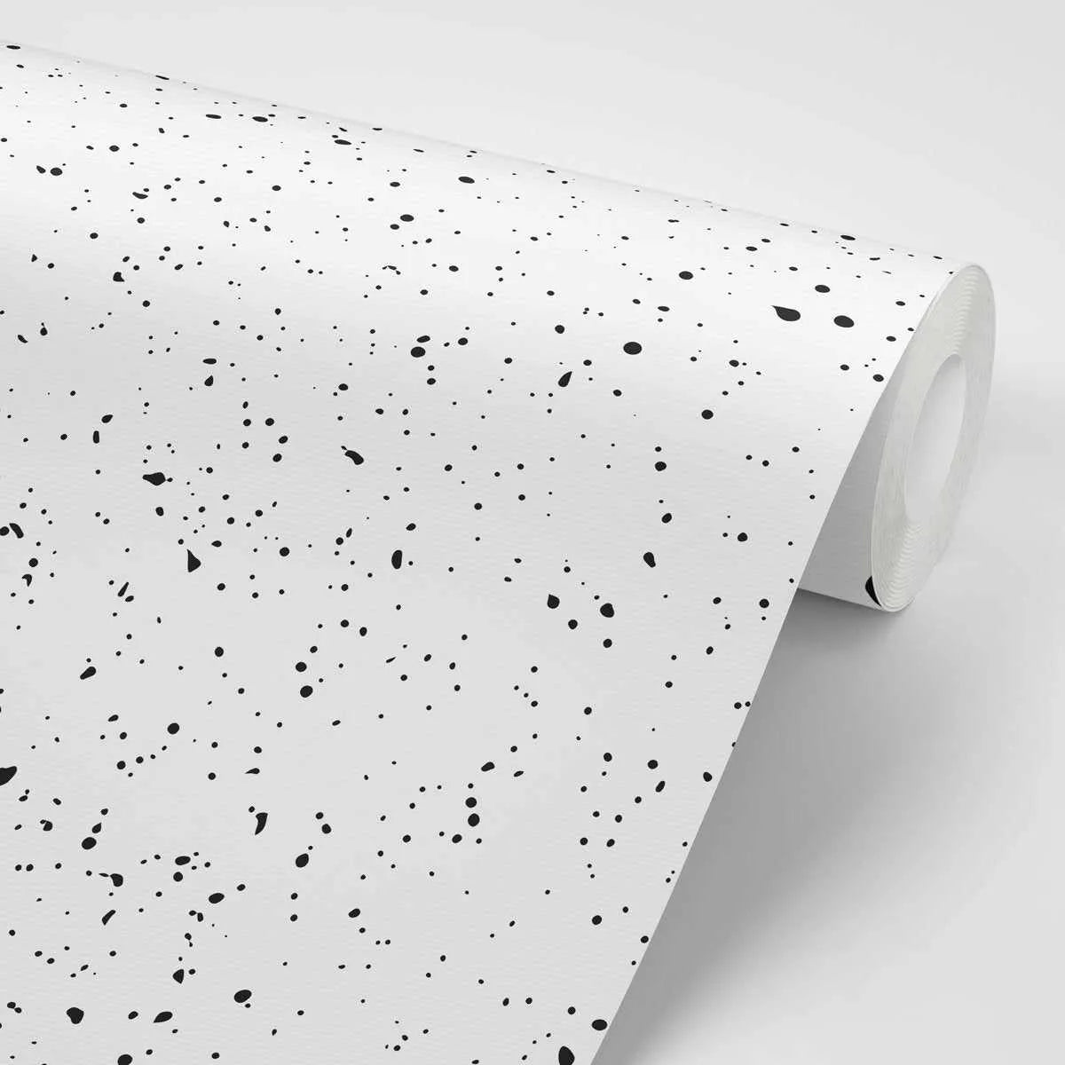 "Roll of peel and stick wallpaper featuring a repeating pattern of irregular black ink splatters and dots of varying sizes on a crisp white background. The design has a hand-painted, organic quality with a matte finish."