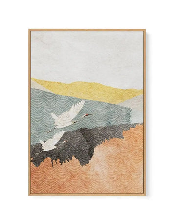Framed canvas art print featuring a Japanese-inspired landscape with two white cranes in flight over layered terrain. The composition shows a pale cream sky at top, golden-yellow hills, soft green water with circular wave patterns, dark charcoal mountains, and rust-orange sand with swirling textures at bottom. The artwork uses muted, earthy tones with intricate line work creating movement throughout. Natural wood frame with subtle grain visible around the edges of the canvas.
