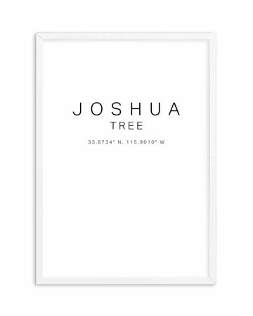 White framed art print featuring minimalist text design. The words "JOSHUA TREE" appear in large, thin sans-serif font, centered on a white background. Below in smaller text reads "TREE" followed by geographic coordinates "33.8734° N, 115.9010° W" in a thin, light typeface. The frame is white with clean edges and appears to have subtle depth, shown against a plain background.