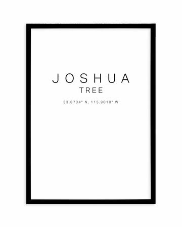 Joshua Tree coordinates art print in black frame. Minimalist design featuring "JOSHUA TREE" in thin, uppercase letters centered on white background, with geographic coordinates "33.8734° N, 115.9010° W" displayed below in smaller text. Clean, modern aesthetic with black wood frame and white interior border.