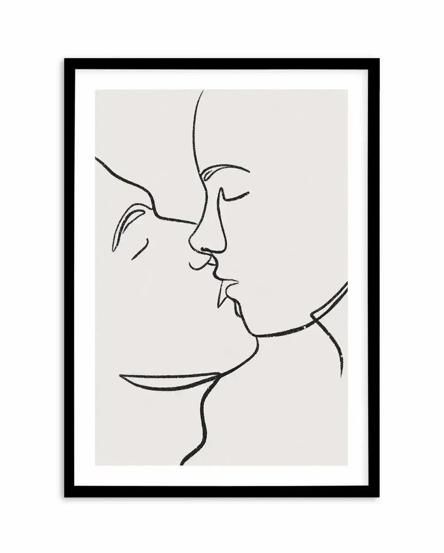Art print featuring a minimalist one-line drawing of two faces in profile, leaning in for a kiss, rendered in black on a light cream background, displayed in a black frame with white border.