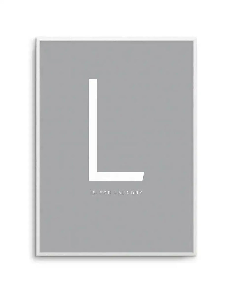 Framed art print featuring a large white letter L in a minimalist sans-serif font centered on a soft gray background. Below the letter, small white text reads "IS FOR LAUNDRY." The artwork is displayed in a white frame with a subtle white border, creating a clean, modern aesthetic suitable for a laundry room or utility space.