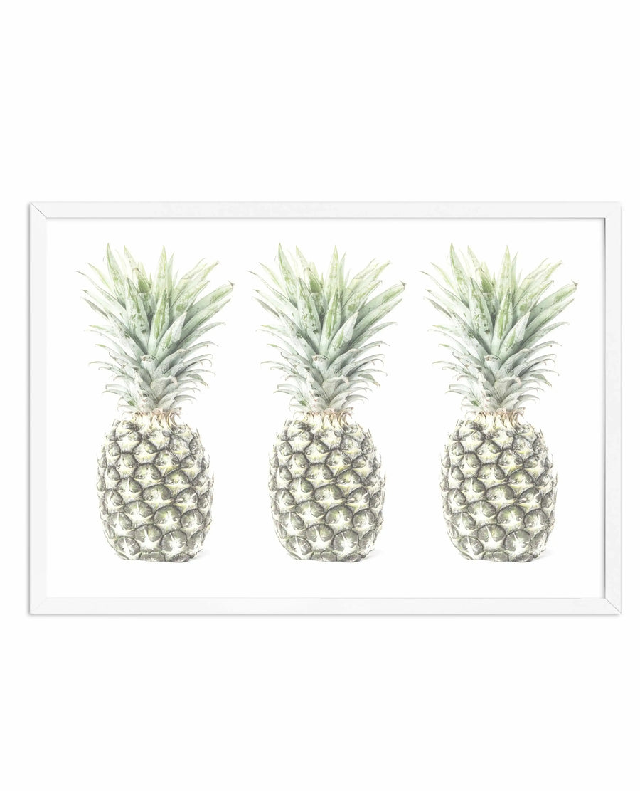 Framed art print featuring three watercolor illustrations of pineapples arranged horizontally against a white background. Each pineapple is rendered in soft green and cream tones with detailed shading on the textured fruit body and delicate leafy crown. The artwork is displayed in a white frame with a white border, creating a clean, botanical aesthetic with a naturalistic yet artistic quality.