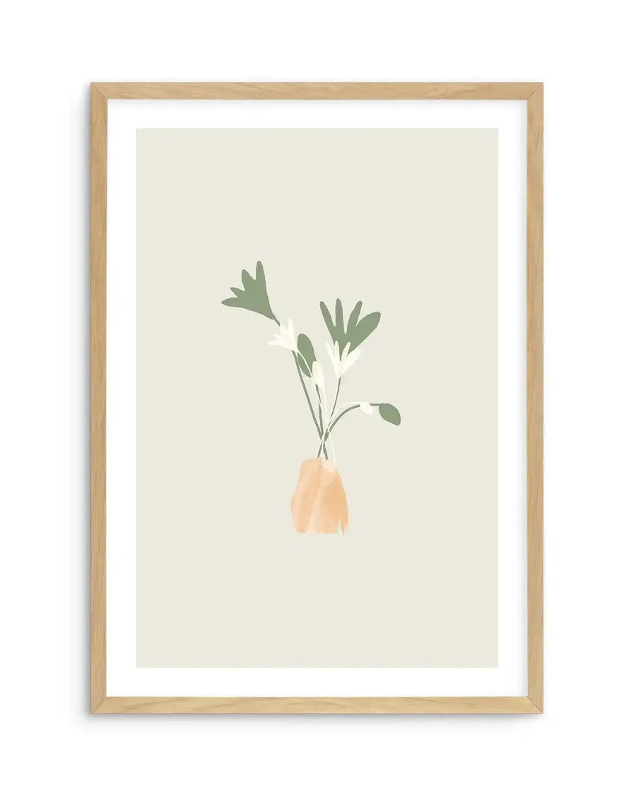 Art print featuring a minimalist illustration of three delicate flowers with pale green leaves and white petals, arranged in a small, abstract peach-coloured vase, on a soft cream background. The print is displayed in a natural oak frame with white border.