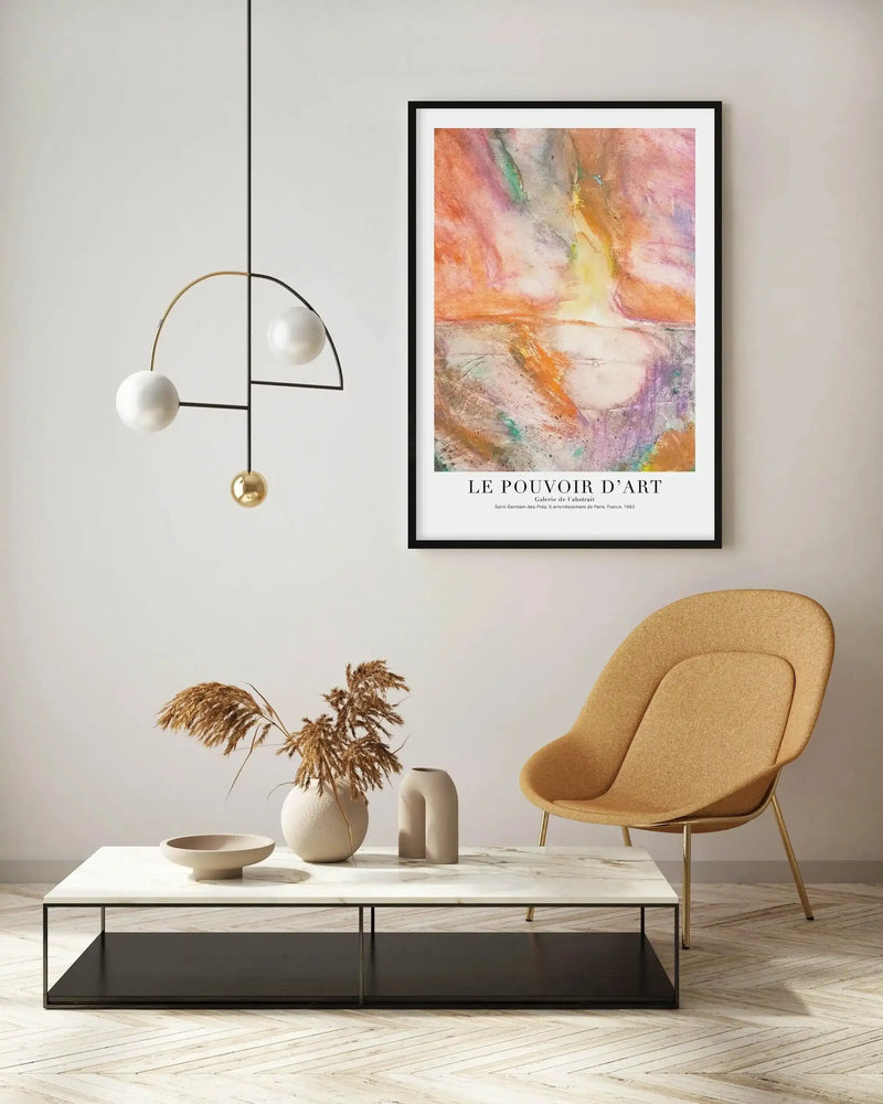 Large framed art print displayed above a white marble coffee table in a minimalist living room. The abstract print features swirling brushstrokes in vibrant orange, pink, purple, and green, creating a dynamic composition suggestive of a sunset over water, with a black frame and white border. The room includes a modern black and gold pendant light, a mustard yellow armchair, and dried pampas grass in a ceramic vase.