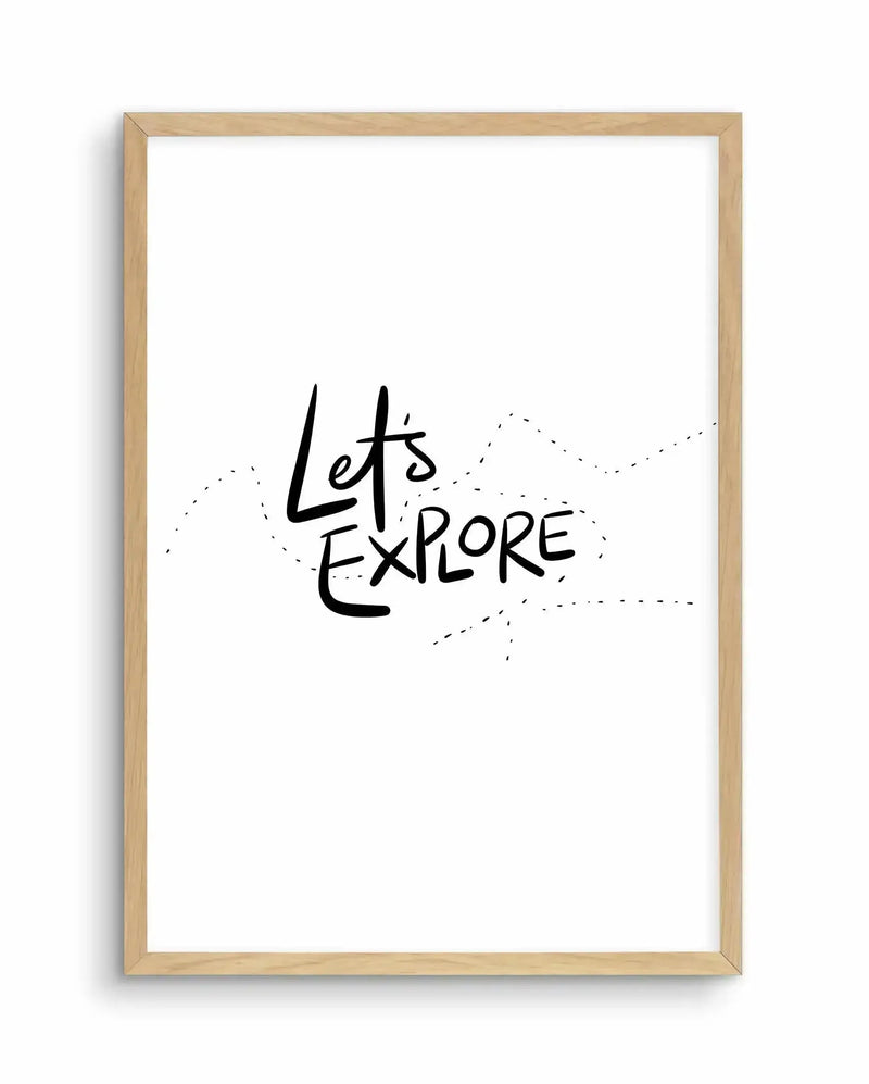 Art print in light natural wood frame featuring hand-lettered black text reading "Let's Explore" centered on white background, with decorative dotted line illustrations suggesting a map or travel route around the text, minimalist design with black ink on white paper.