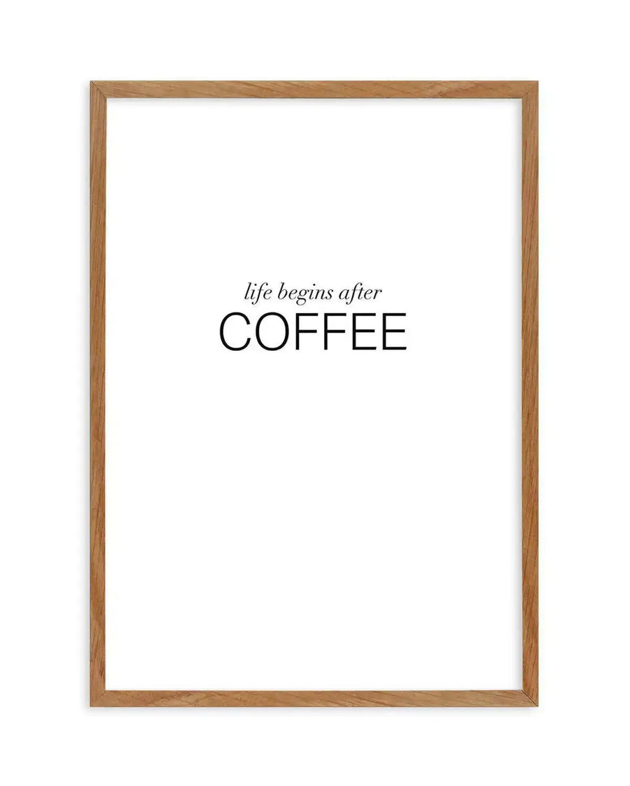 Art print featuring the phrase "life begins after COFFEE" in black text on a white background, displayed in a natural oak frame with white border. The word "life begins after" is in a delicate, italicized serif font, while "COFFEE" is in a bold, sans-serif uppercase font.