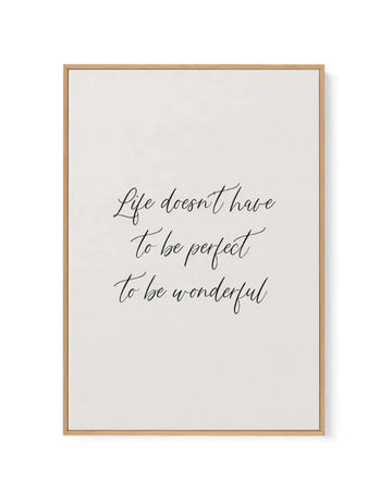 Framed canvas art print with a natural wood frame displaying handwritten script text in dark gray that reads "Life doesn't have to be perfect to be wonderful" centered on a cream-colored background with white border. The text uses a flowing, cursive calligraphy style. The wood frame has a light tan finish with visible grain texture.