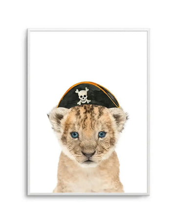Watercolour art print featuring a cute baby lion cub with blue eyes wearing a black pirate hat with a white skull and crossbones emblem, set against a plain white background and displayed in a white frame with a white border.