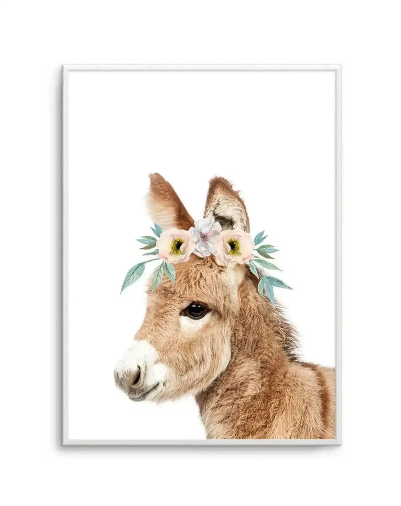Watercolour art print featuring a baby donkey with soft brown fur and large dark eyes, wearing a delicate flower crown with pale pink and white blooms and sage green leaves, displayed in a white frame with white border.