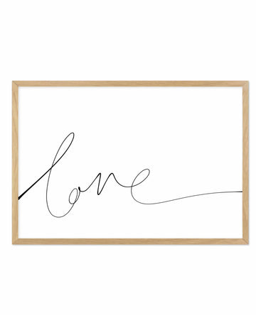 Hand-scripted art print with the word "Love" written in flowing, continuous black line script against a white background, framed in a natural wood frame with white border. The lettering is elegant and minimalist with organic, curved letterforms that create a single connected line drawing.