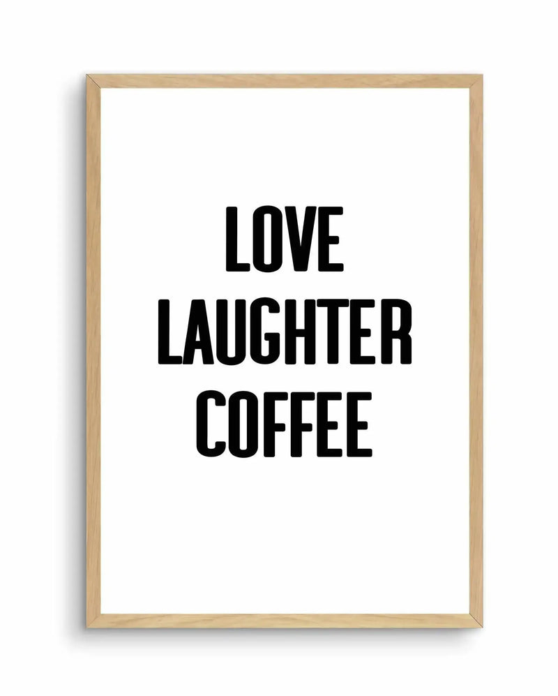 Art print with black sans-serif typography on white background, framed in light natural wood. Text reads "LOVE LAUGHTER COFFEE" in three centered lines. Frame has a simple profile with visible wood grain texture and grain shadow on left edge, creating depth against white background.