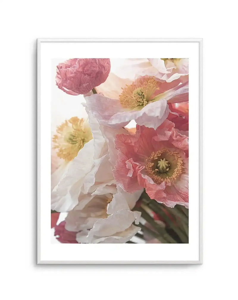 Framed photography art print featuring a close-up bouquet of delicate poppies in shades of soft pink, white, and pale yellow, with a white frame and white border. The composition highlights the ruffled petals and intricate centers of the flowers, creating a light and airy feel.