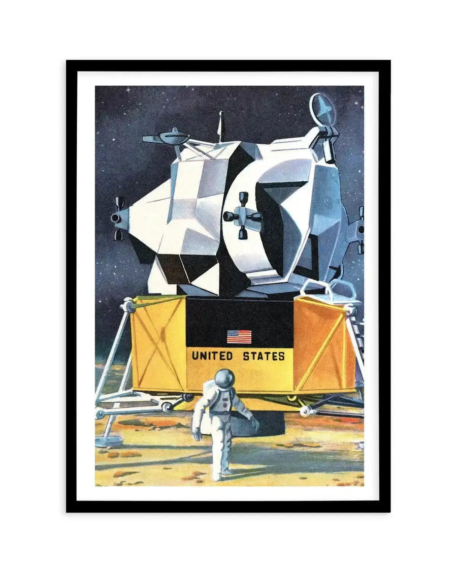 Art print featuring a retro-futuristic illustration of an astronaut standing on the moon next to a lunar lander, with a starry dark blue sky in the background. The lunar lander is predominantly white and grey with geometric panels, and has a yellow base with "UNITED STATES" and an American flag printed on it. The astronaut is in a white spacesuit, facing away from the viewer. The print is displayed in a black frame with a white border.