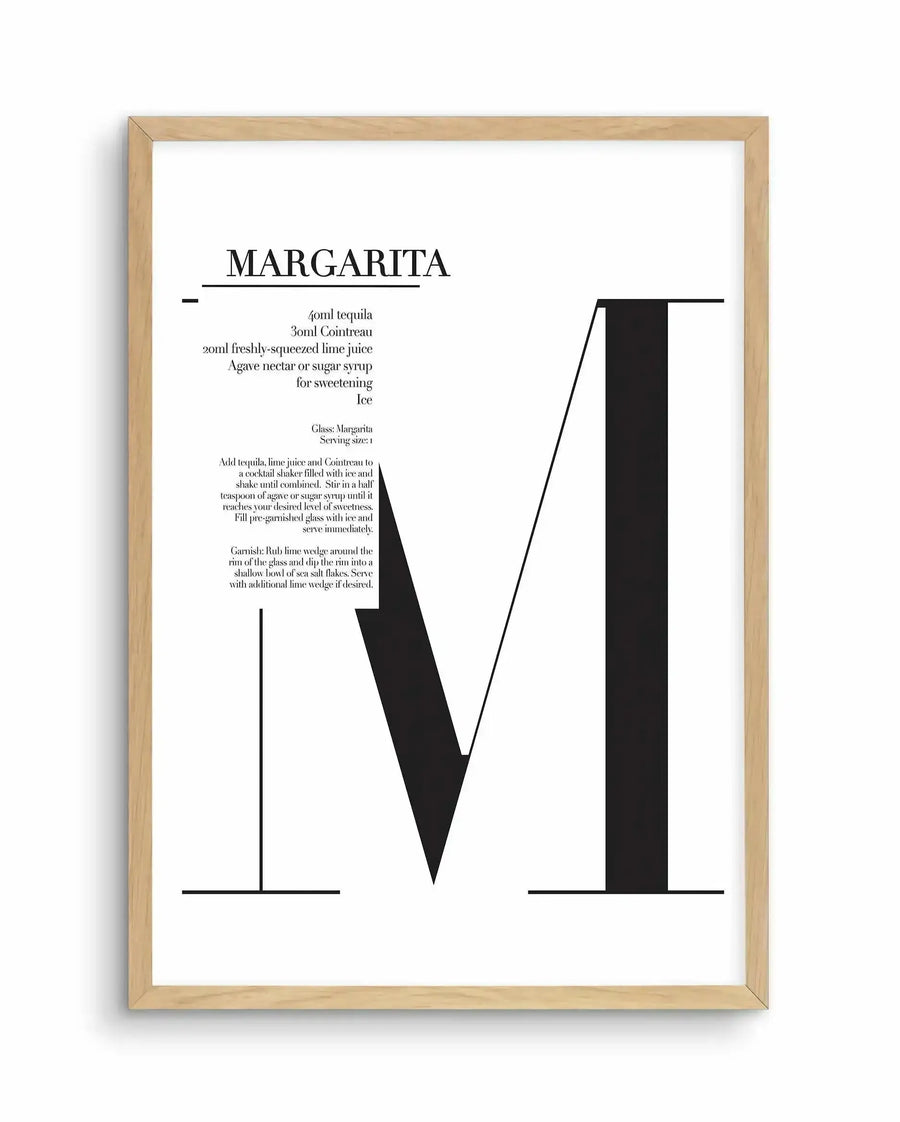 Margarita art print in natural wood frame featuring minimalist black and white geometric illustration. The design displays the word "MARGARITA" at top in serif font, followed by ingredient list and preparation instructions in small text. Below is a stylized cocktail glass composed of bold black shapes forming a V-shaped bowl and rectangular stem. The composition uses clean lines and negative space against a white background. The natural wood frame has a light tan finish with visible grain texture.