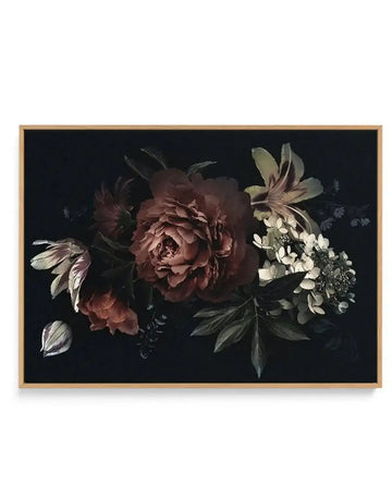 Gallery-wrapped canvas print featuring a dark, moody botanical illustration of a floral arrangement on a deep black background, displayed in a natural oak frame. The arrangement includes a large, central peony in rich burgundy and deep rose hues, surrounded by smaller flowers and foliage in muted greens, creams, and subtle purples, with a single white petal resting at the bottom left.