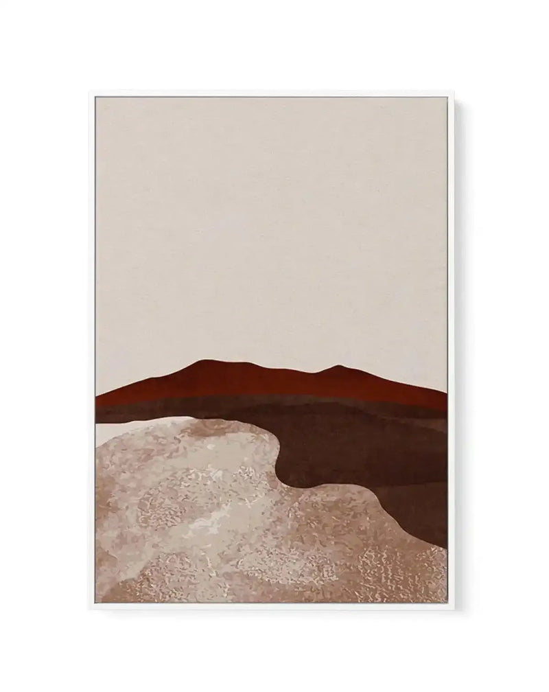 Framed canvas art print titled Midnight Desert II featuring a minimalist desert landscape. The composition shows layered rolling hills in deep brown and burnt sienna tones against a pale beige sky. The foreground depicts sandy desert terrain with subtle tan and cream textures and organic undulating shapes. A gray frame with white border contains the artwork. The overall aesthetic is calm and muted, with a modern, simplified approach to landscape representation.