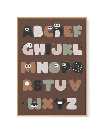 Framed canvas art print featuring the alphabet A to Z displayed vertically on a warm brown background. Each letter is illustrated as a friendly monster character in varying colors including cream, tan, sage green, black, and gray, with expressive eyes and playful details. The wooden frame is natural tan with a white border. Illustration style with a whimsical, child-friendly design.