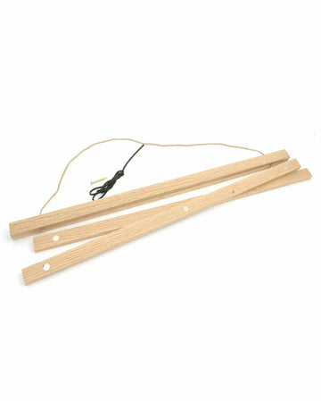 Oak wood poster hanger with natural light wood finish, consisting of three wooden slats with small circular holes for hanging. Black cord with metal connectors attached to the top slat. The hanger is displayed at an angle against a white background, showing the natural wood grain texture and warm honey-toned finish. Designed to suspend art prints or posters.