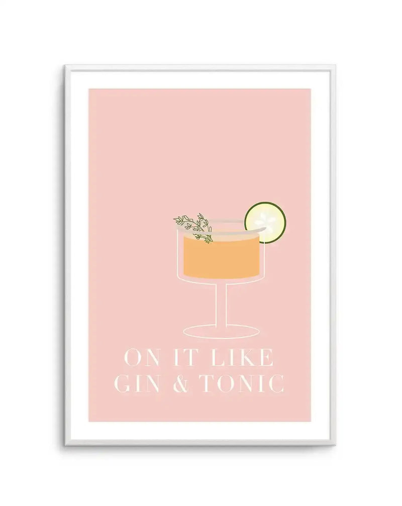 Art print featuring a minimalist illustration of a cocktail glass with an orange drink, garnished with a sprig of herbs and a cucumber slice, set against a soft blush pink background. The text "ON IT LIKE GIN & TONIC" is printed in white below the glass. The print is displayed in a white frame with a white border.