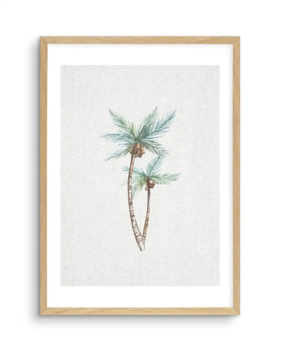 Watercolour art print featuring two palm trees with light blue-green fronds and brown coconuts, set against a textured off-white background, printed on fine art paper and displayed in a natural oak frame with white border.