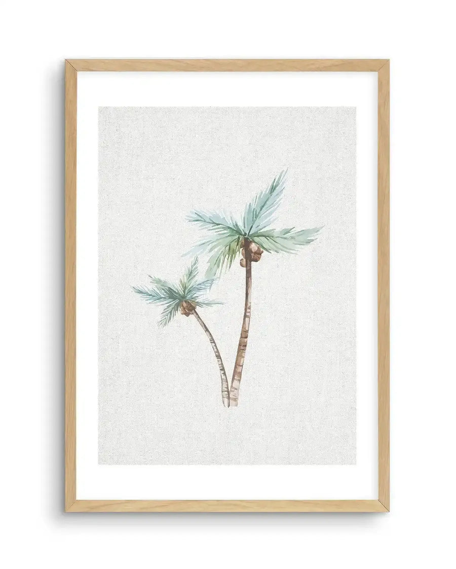 Watercolour art print featuring two palm trees with light blue-green fronds and brown trunks, on a textured off-white background, printed on fine art paper and displayed in a natural oak frame with white border.