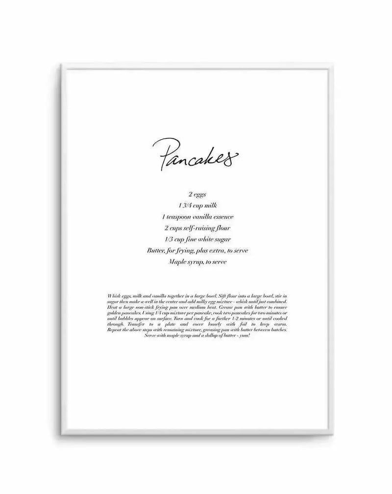 Framed art print featuring a handwritten-style recipe for pancakes on white background. The word "Pancakes" appears in elegant script at the top. Below are listed ingredients including 2 eggs, 1 3/4 cup milk, 1 teaspoon vanilla essence, 2 cups self-raising flour, 1/3 cup fine white sugar, and butter for frying. Detailed cooking instructions appear in smaller italic text in the lower portion. The design uses black ink on cream-colored paper, enclosed in a light gray frame with white border.