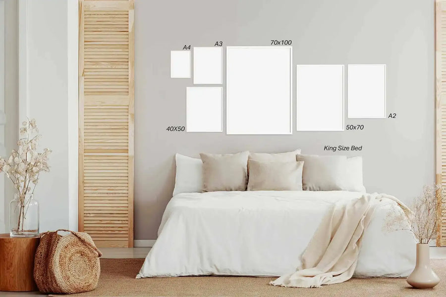Gallery wall displaying six framed canvas art prints in varying sizes arranged above a king-size bed with cream linens. Frames shown are gray with white borders in sizes labeled A4, A3, 70x100 centimeters, 40x50 centimeters, 50x70 centimeters, and A2. Bedroom features light gray walls, wooden louvered screens on either side, natural fiber basket, dried flowers in clear glass vase, and neutral earth-tone bedding and accessories creating a calm, minimalist aesthetic.
