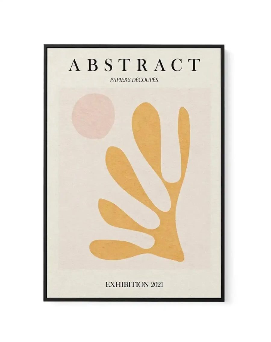 Framed canvas art print featuring abstract minimalist design with a dusty rose circular shape in upper left and golden yellow organic curved forms below against a cream background. Black frame with white border. Text reads "ABSTRACT PAPIERS DÉCOUPÉS" at top and "EXHIBITION 2021" at bottom in serif typography. Matte finish with contemporary gallery aesthetic.