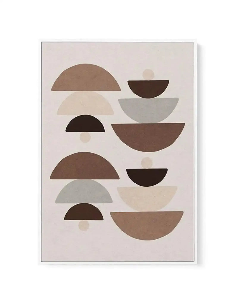 Framed canvas art print featuring an abstract geometric composition of stacked semicircles and circles in earth tones. Left column displays six overlapping half-circles in varying sizes in warm brown, cream, black, and gray tones, each with a small circular accent below. Right column shows a vertical stack of five larger bowl-shaped semicircles in similar colors. Soft beige background with muted, neutral palette. Illustration style with flat color fills. Gray frame with white border visible around edges.