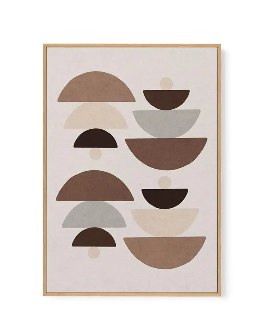 Framed canvas art print featuring an abstract geometric composition of stacked semicircles and circles in warm earth tones including taupe, warm brown, dark brown, cream, and soft gray on a pale beige background. The design is arranged in two vertical columns with overlapping organic shapes creating a balanced, minimalist aesthetic. Natural wood frame with white border visible around the canvas edges.