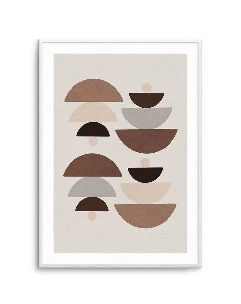 Abstract art print featuring stacked semi-circular and bowl shapes in various shades of brown, beige, and grey on a light cream background, displayed in a white frame with a white border. The composition shows two vertical columns of stacked shapes, each stack comprising three elements, with small, light circles interspersed between some of the shapes.