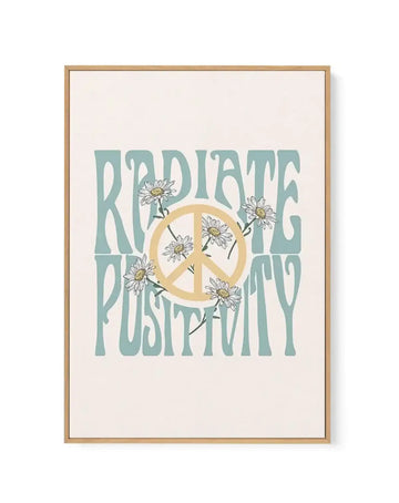 Framed canvas art print with natural wood frame displaying "Radiate Positivity" text in sage green. A golden peace symbol is centered with hand-drawn white daisies with yellow centers scattered throughout the composition. Cream background with white border around the artwork.