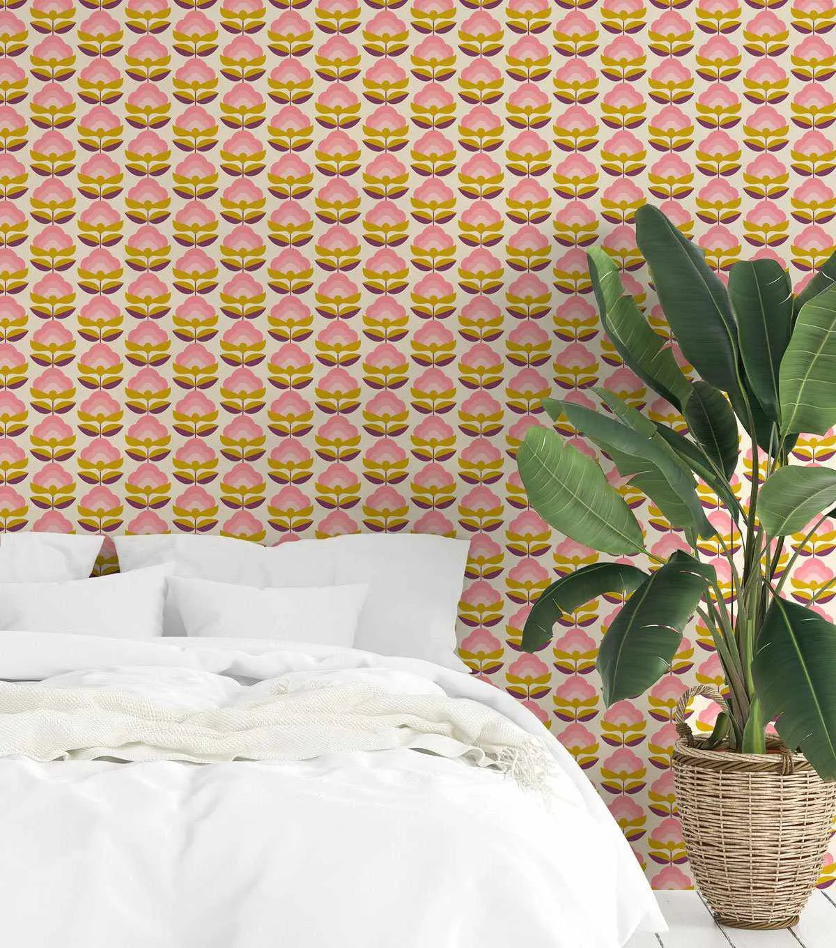Bedroom with a bed dressed in white linen and a large green plant in a woven basket, featuring a wallpaper with a repeating pattern of retro lotus flowers in shades of pink, mustard yellow, and deep purple on a cream background.