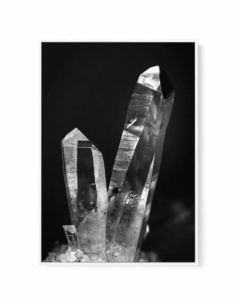 Black and white close-up photograph of two clear quartz crystal points with natural striations and faceted surfaces against a dark background, displayed as a framed canvas print with white border and black frame.