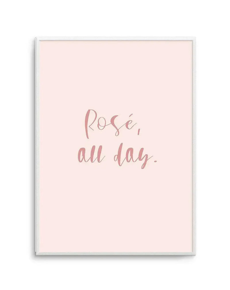 Framed art print with a soft blush pink background featuring handwritten-style text in dusty rose that reads "Rosé, all day." The print is mounted in a silver-toned frame with a white border.