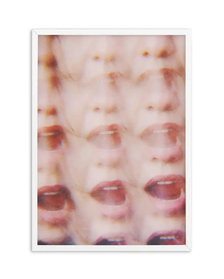 Art print featuring a blurred, multi-layered image of a person's face, primarily focusing on the mouth and nose, repeated in rows. The composition creates a sense of motion and distortion, with soft, muted tones of pale pink, peach, and hints of red, printed on fine art paper and displayed in a white frame with white border.