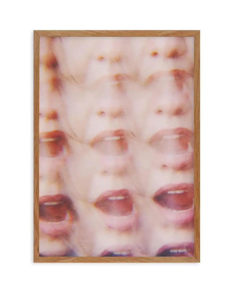 Abstract art print featuring a repeated, blurred image of a person's face with open mouth, creating a distorted, layered effect in shades of pale pink, red, and brown, printed on fine art paper and displayed in a natural oak frame with white border.