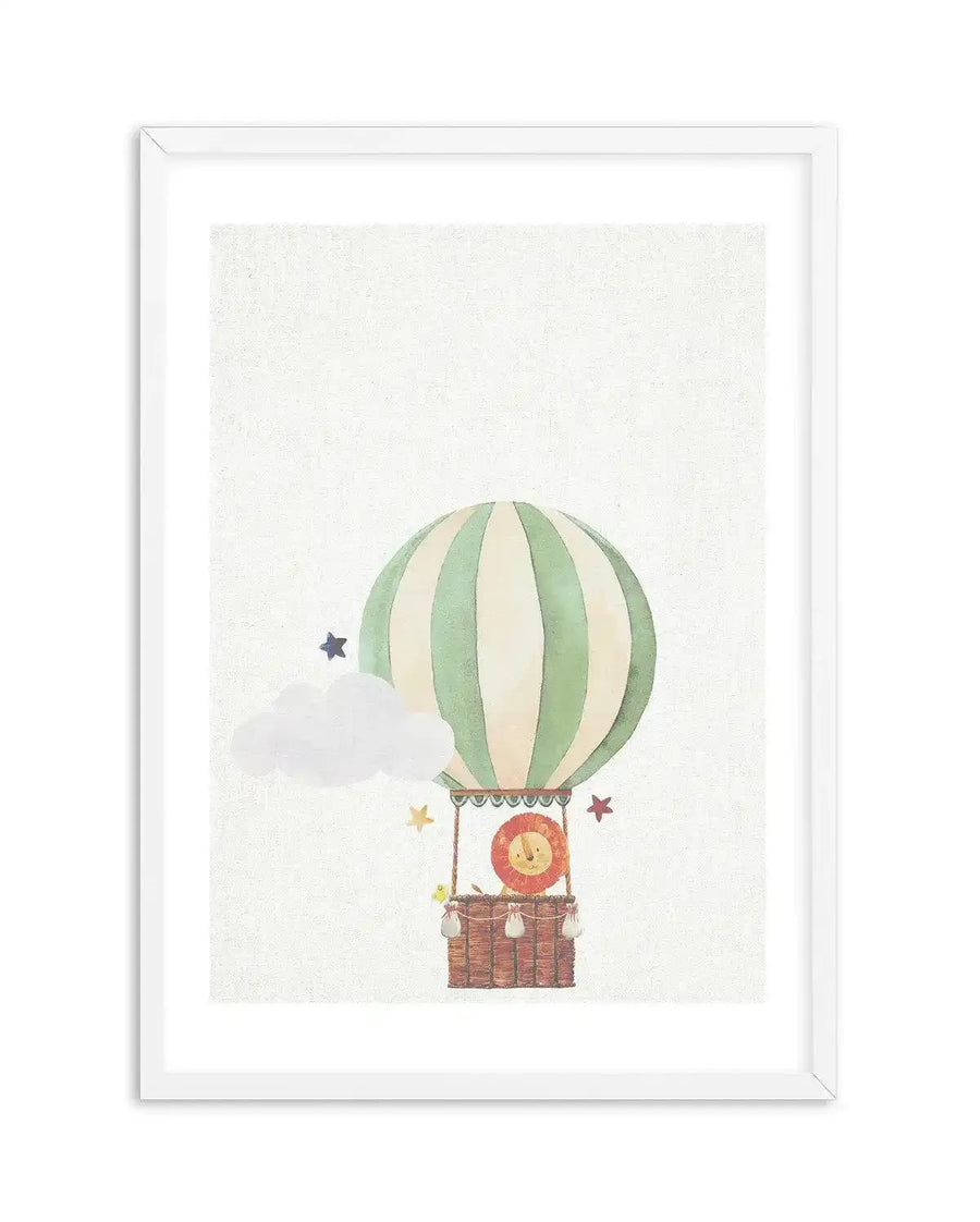 Watercolour art print featuring a hot air balloon with vertical cream and sage green stripes, carrying a cheerful lion in a woven basket. A fluffy white cloud and scattered stars in blue, yellow, and red accompany the balloon, all set against a textured white background, displayed in a white frame with a white border.