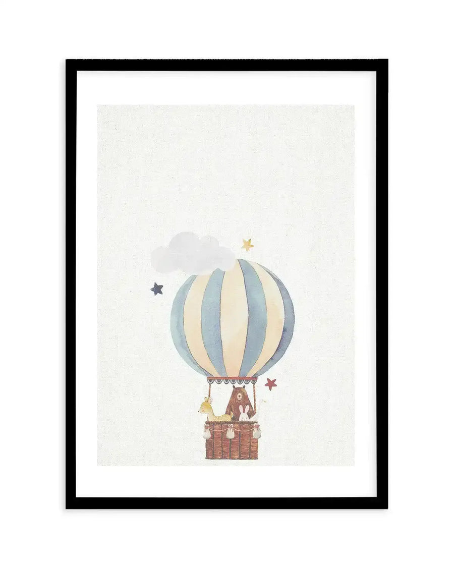 Watercolour art print featuring a hot air balloon with blue and cream stripes, carrying a bear, a deer, and a rabbit in its woven basket. The background is a textured cream, with a white cloud and scattered gold and blue stars, displayed in a black frame with a white border.