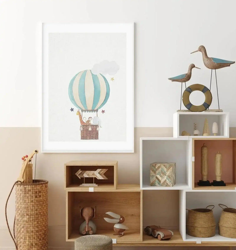 Children's Room:
"Framed art print displayed on a two-toned wall in a child's room, above a wooden shelving unit with various decorative items. The print features a watercolour illustration of a hot air balloon with light blue and cream stripes, carrying a giraffe, monkey, and elephant in its basket, surrounded by small stars and clouds, with a white frame and white border."