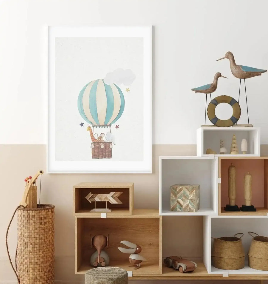 Children's Room:
"Framed art print displayed on a two-toned wall in a child's room, above a wooden shelving unit with various decorative items. The print features a watercolour illustration of a hot air balloon with light blue and cream stripes, carrying a giraffe, monkey, and elephant in its basket, surrounded by small stars and clouds, with a white frame and white border."