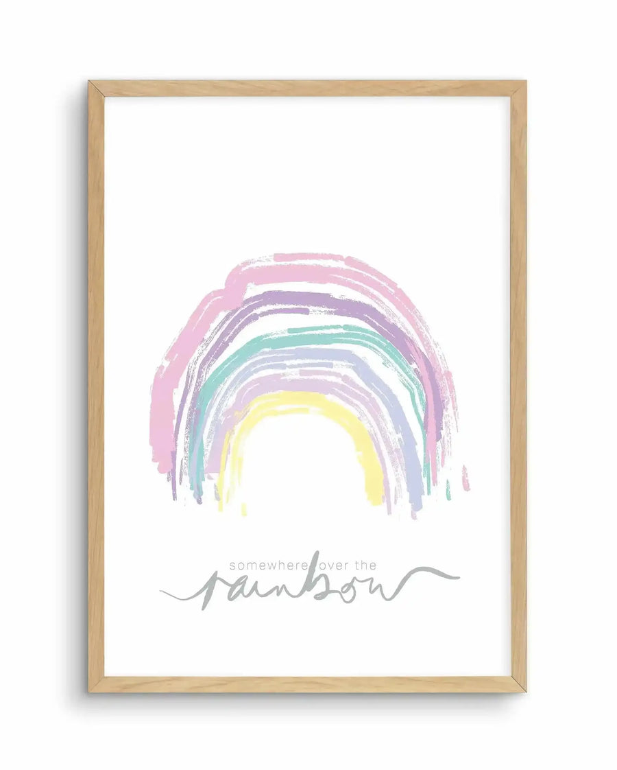 Framed art print featuring a hand-painted rainbow with soft, watercolour-style brushstrokes in pastel pink, purple, lavender, mint green, and pale yellow, centered on a white background. Below the rainbow, gray cursive text reads "somewhere over the" with "rainbow" in larger, flowing script. The artwork is displayed in a natural wood frame with a white border.